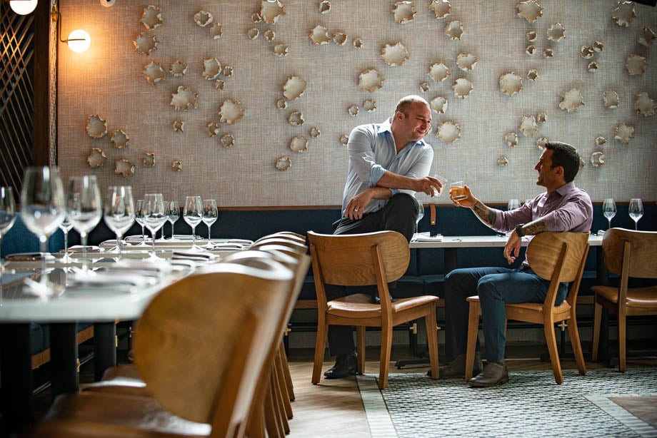 Photo of two men sharing a drink in a restaurant taken by Chicago-based lifestyle photographer John Boehm. 