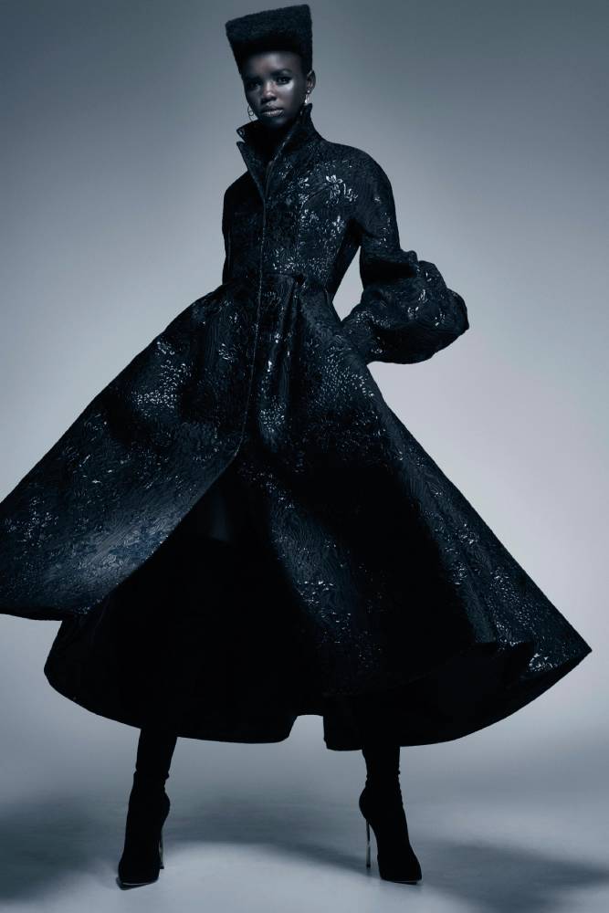 A photo by Juli Bala of a woman wearing a long flowing black coat.