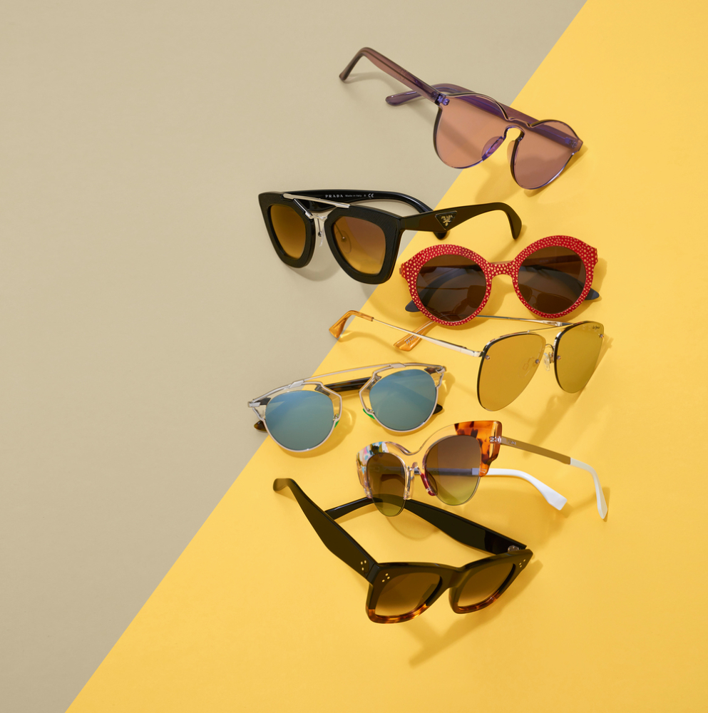 A color photo by Justin Gomler of an arrangement of sunglasses at different angles against a grey and yellow background.