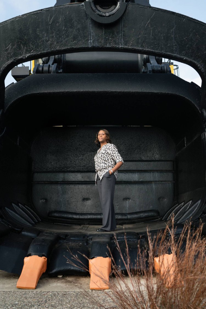 Photo by Kat Schleicher of a woman standing in the front of a massive construction vehicle
