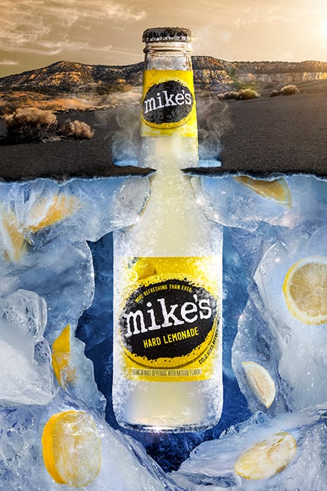 An image showing the landscape of a Tucson, Arizona desert, with focus on a bottle of Mike's Hard Lemonade digitally emerging from the surface