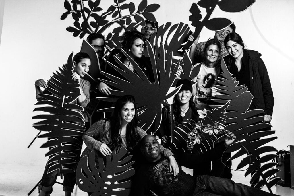Black and white image of Kirsten Miccoli and her team posing with elements from one of her jungle scene set designs.