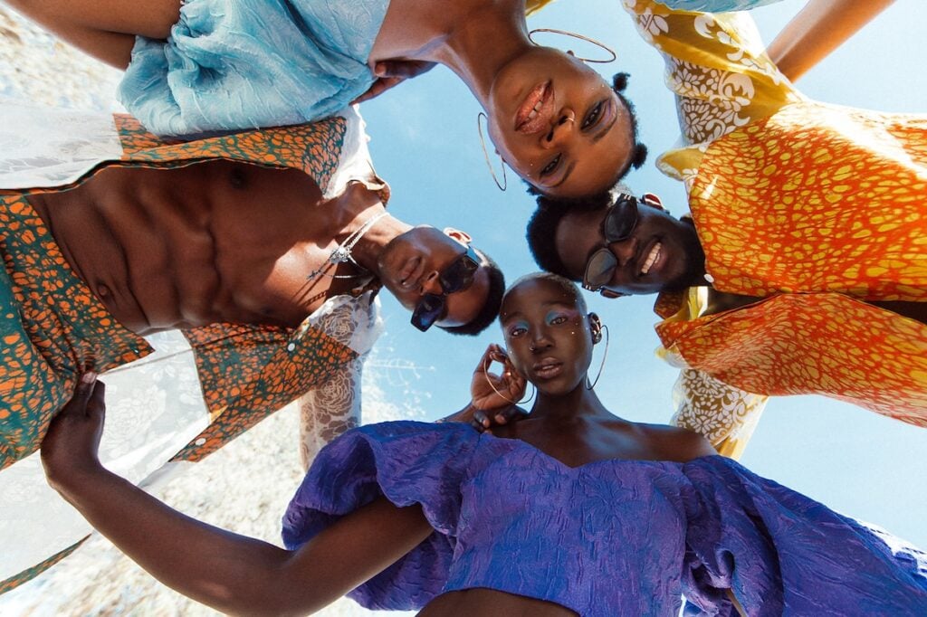 Photo by Mariah Jelena, showcasing four models in colorful clothing from a frog's-eye view.