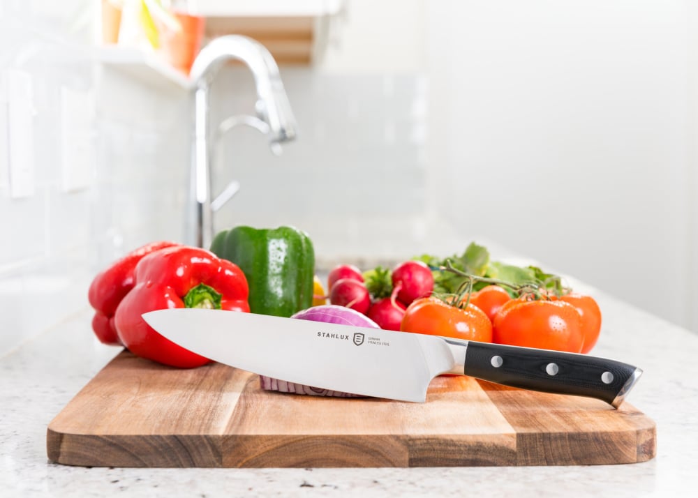 Photo by Mark Bowers of a knife in front of vegetables on a cutting board.