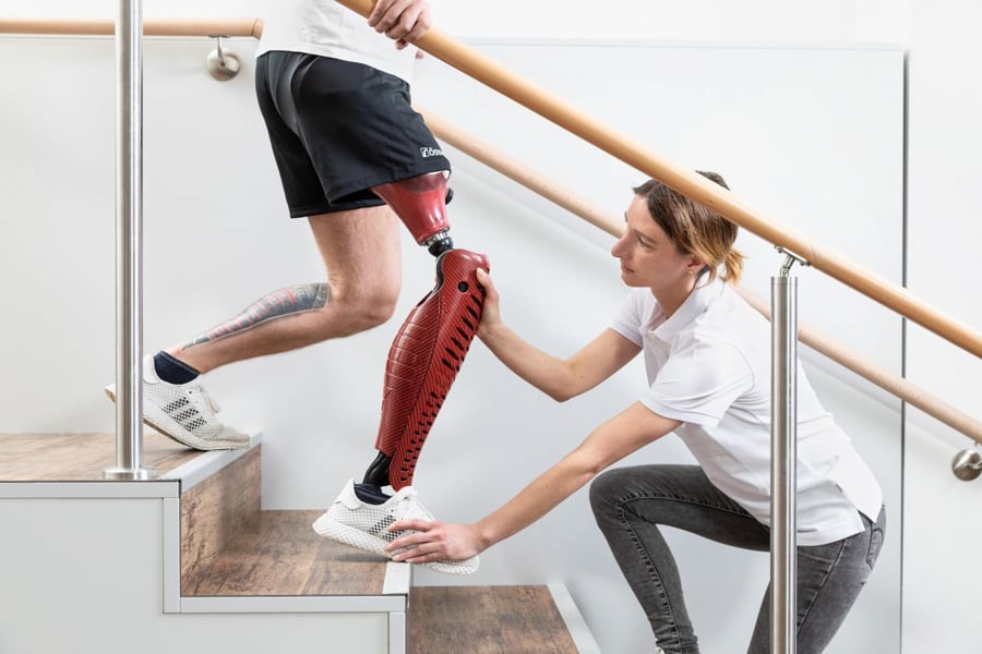 Photo of a woman adjusting the prosthetic leg of a man descending a flight of stairs by Berlin, Germany-based photographer Markus Altmann. 