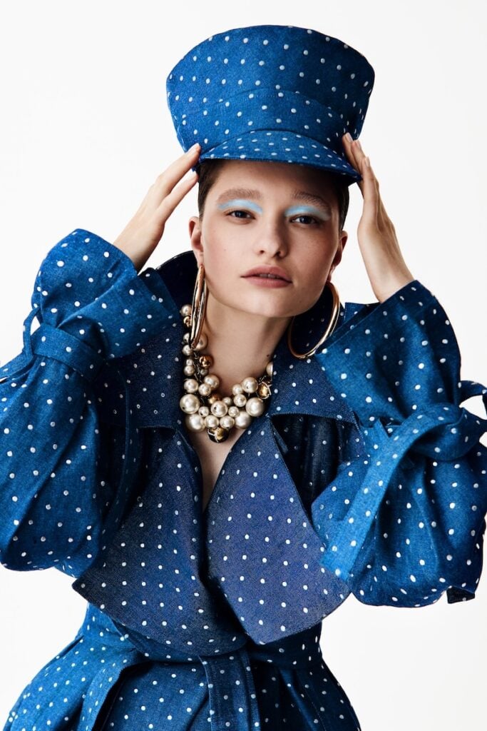 Photo by Mattia Holm, showcasing a model wearing a blue polkadot hat and trench coat. 