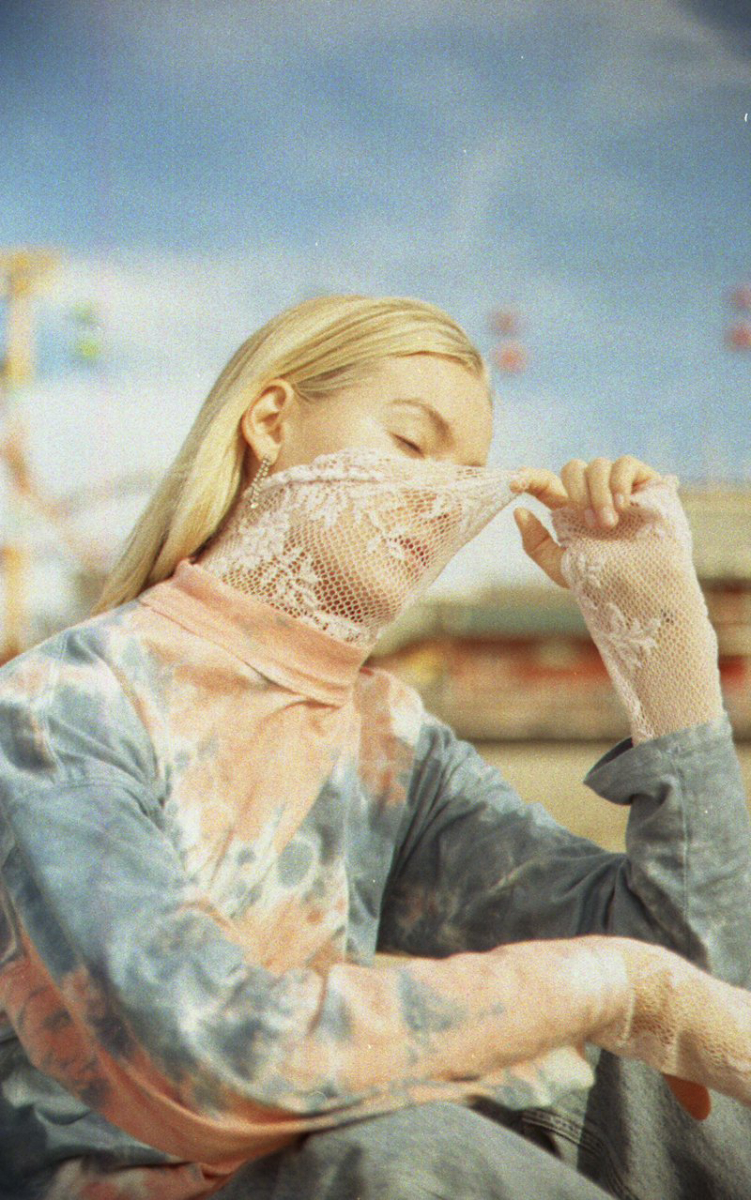 Image by one of the best Fashion photographers in San Francisco Nastasi Dusapin. It depicts a woman pulling a lace shirt over her face outdoors in natural light. 