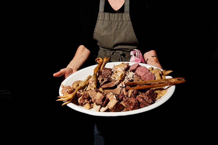 Photo of a chef holding a large dish full of various meats taken by New York-based food photographer Paul Crispin Quitoriano. 