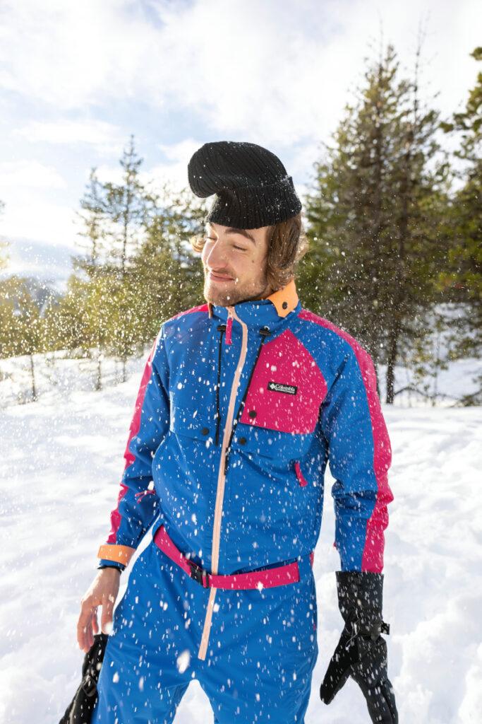 In this candid shot, a man dresses in the Columbia Sportswear Heritage Collection ski suit, enveloped by delicate snowflakes swirling around him, adding a touch of whimsy to the wintry scene.