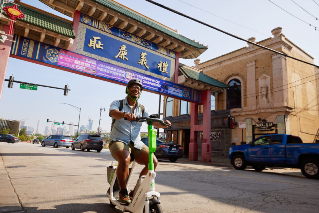 A man riding through the vibrant streets of Chicago's Chinatown on Lime's electric scooter, image by Ricky Klüge.