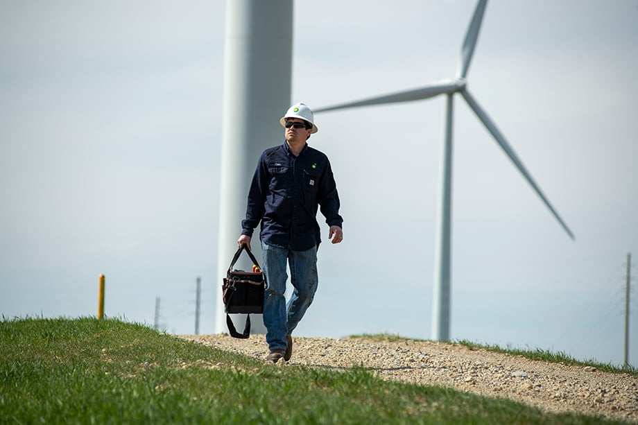 A worker on BP wind farms in Kansas walks across he grass carrying a toolbag shot by Sean F. Boggs