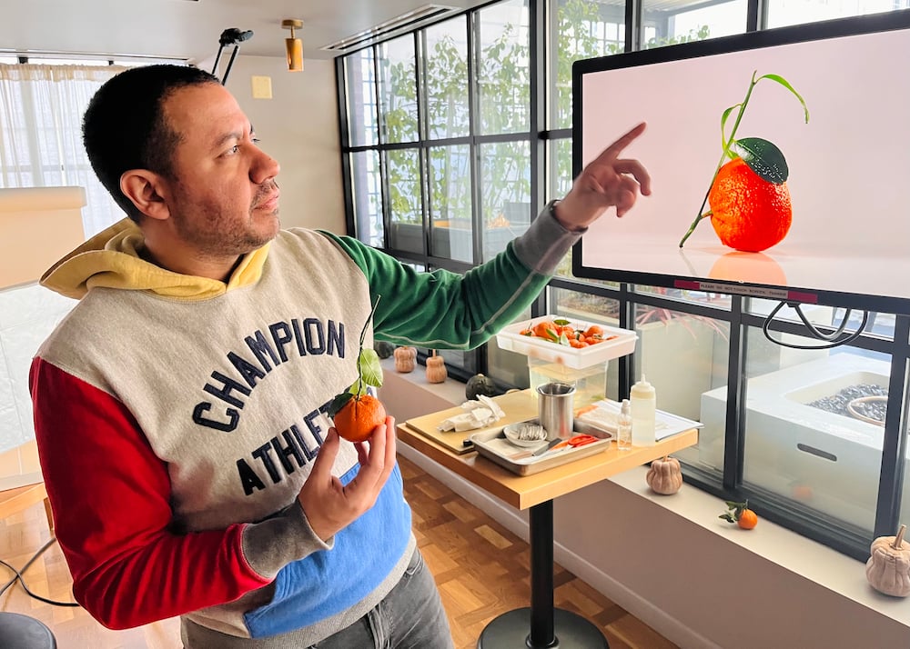 A BTS image of photographer Rey Lopez assessing an image he had just taken of a mandarin while on the shoot production.