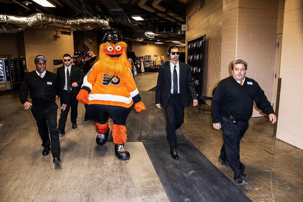 Photo by Steve Boyle of mascot Gritty backstage being led by security.
