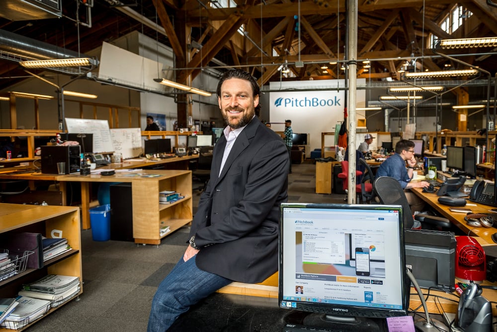 Photo of Pitchbook's CEO sitting on a desk in their casual, converted office.