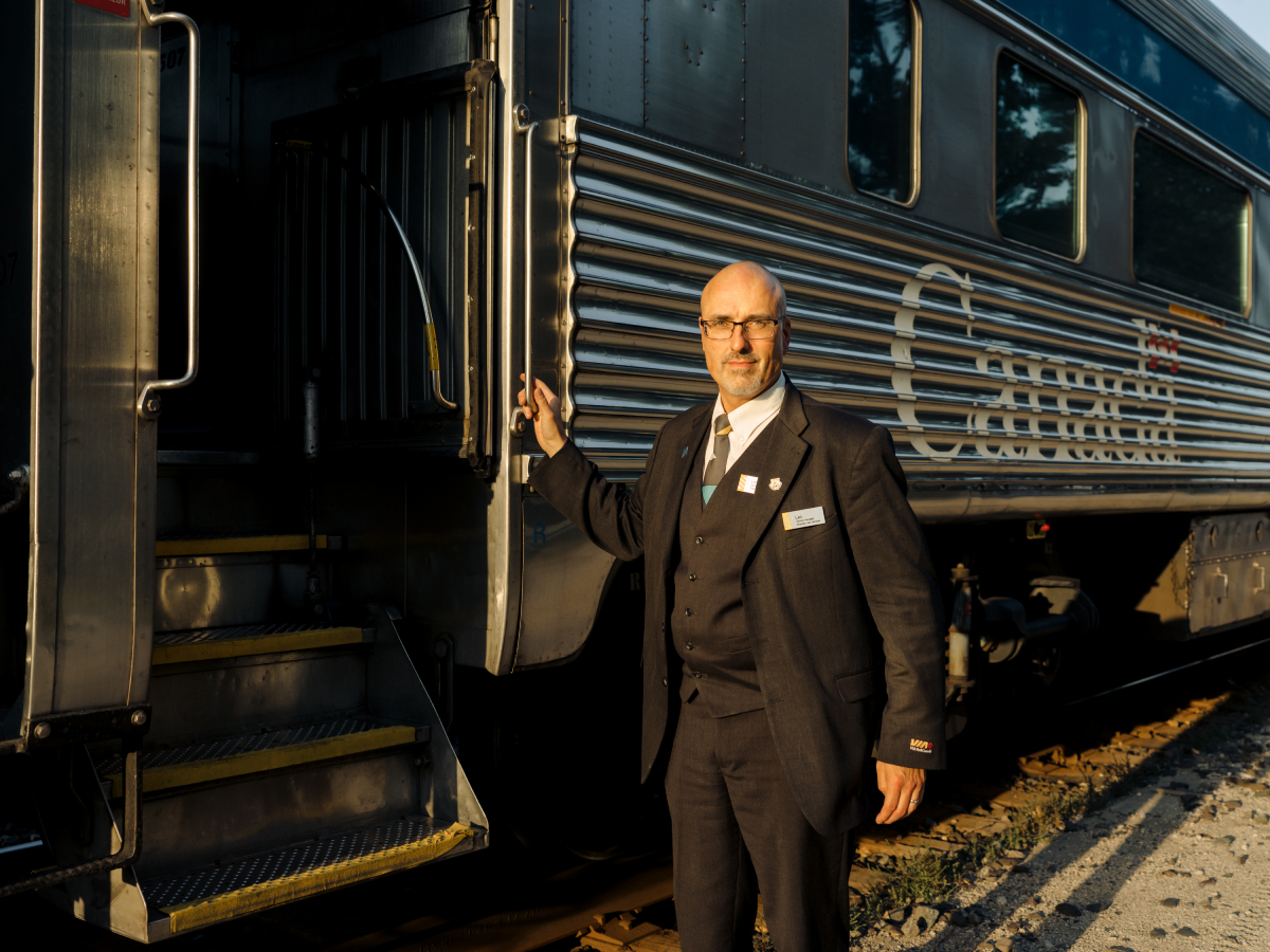 A color photo by Taylor Roades of a train conductor posing outside of the train.