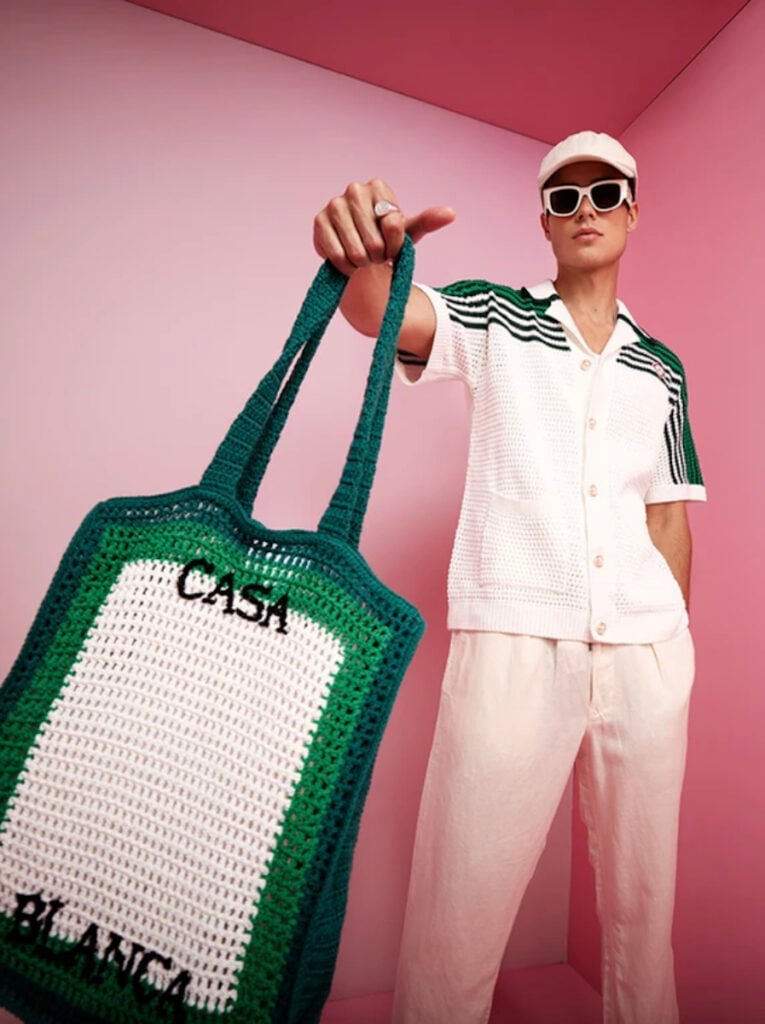Photo by Vaughan Treyvellan, showcasing a model in front of a pink backdrop holding a Casablanca tote bag.