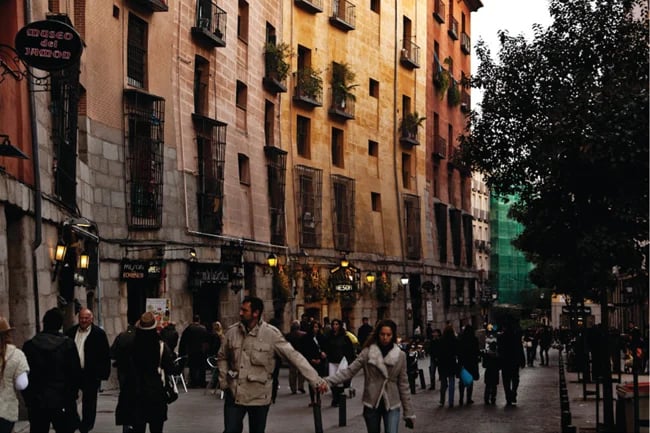 image of people walking down a street in Spain, with a couple holding hands in the center of the photograph